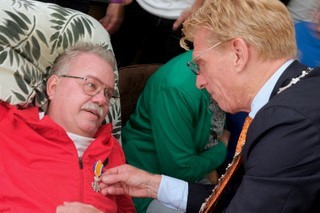 Jan van Maaren liggend in bed met slangetje in neus krijgt lintje opgespeld door burgemeester Bakermans