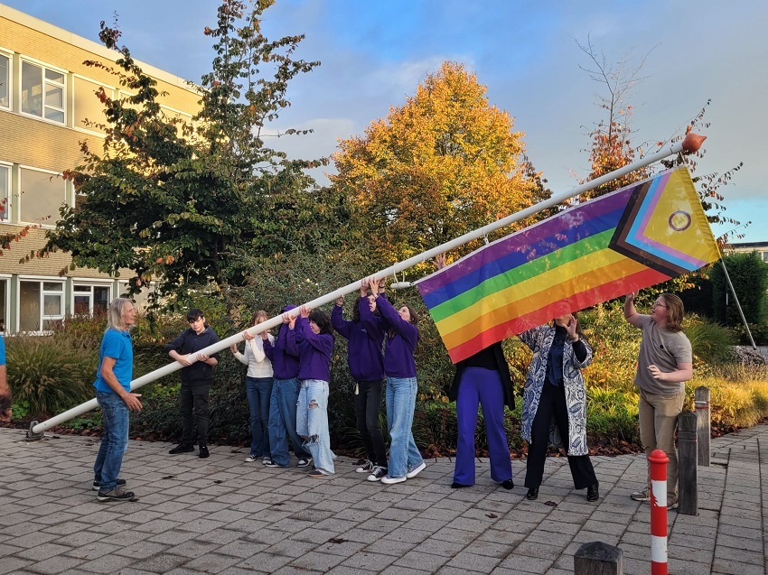 Leerlingen met wethouder en leerkracht hijsen op het plein voor het Cambium college de regenboogvlag