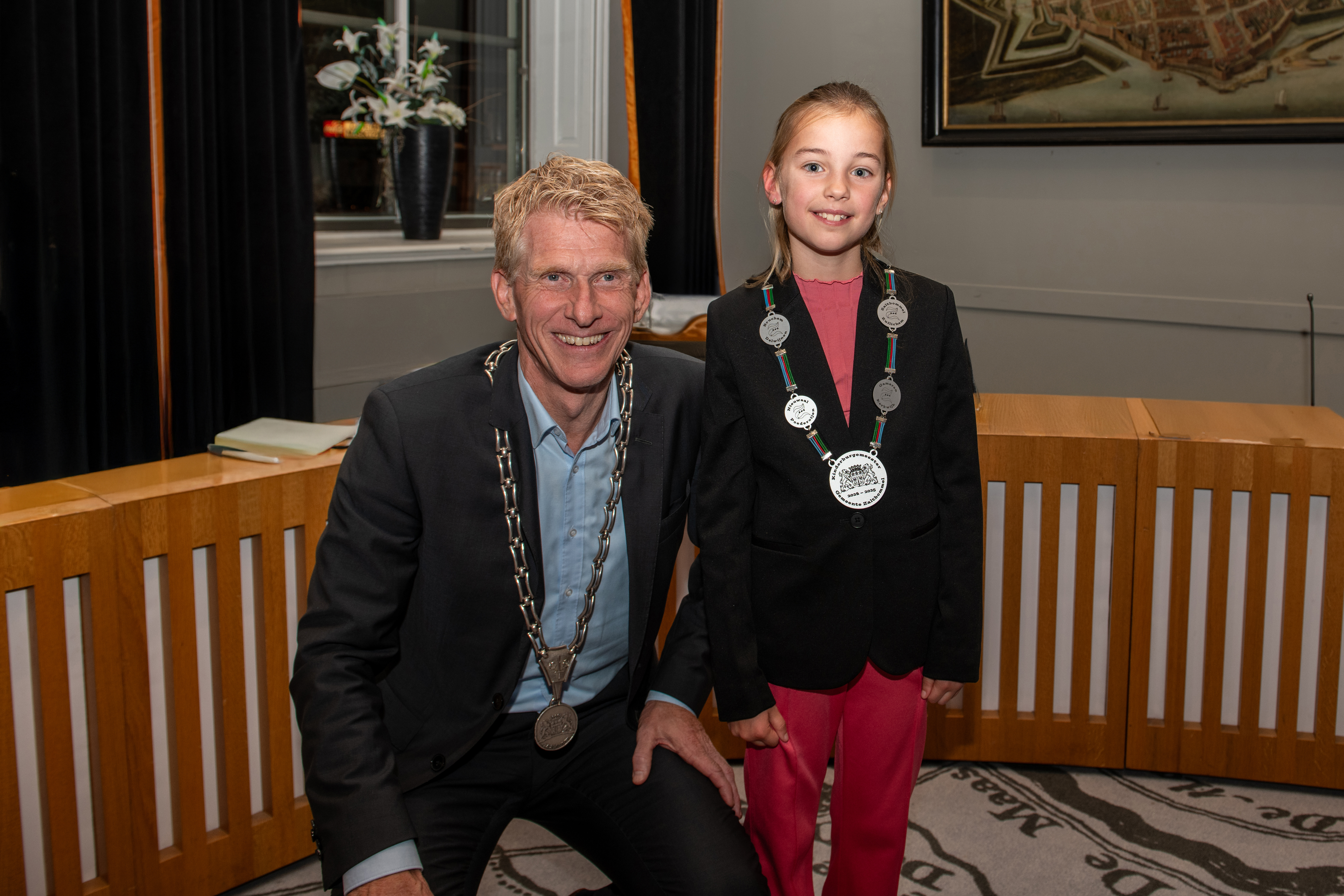 Liz, de nieuwe kinderburgemeester met kinderambtsketting  om en links van haar door knieën burgmeester Bakermans