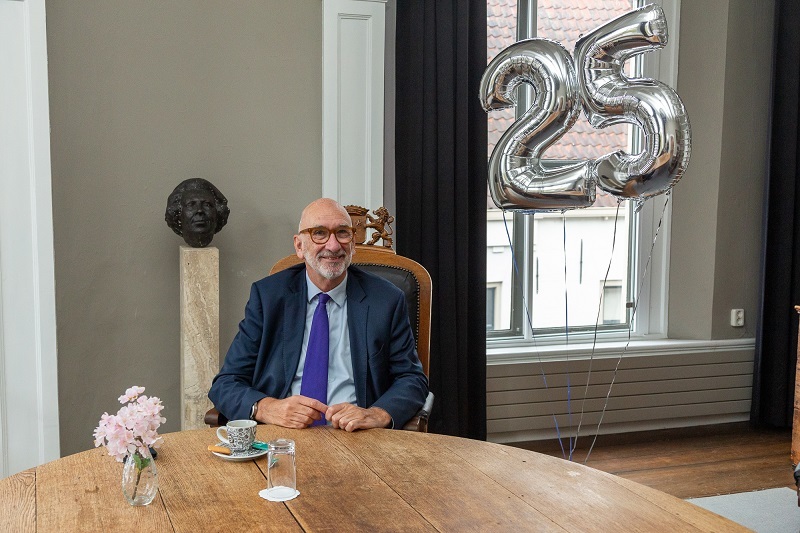 Oud Burgemeester Albert van den Bosch zit op het oude Stadhuis aan een tafel met zilveren ballonnen met cijfers 2 en 5